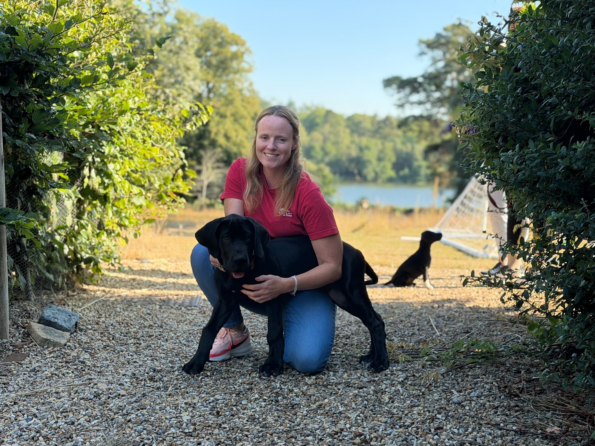 Julie Turner of We Love Pets West Berkshire kneeling with a black puppy
